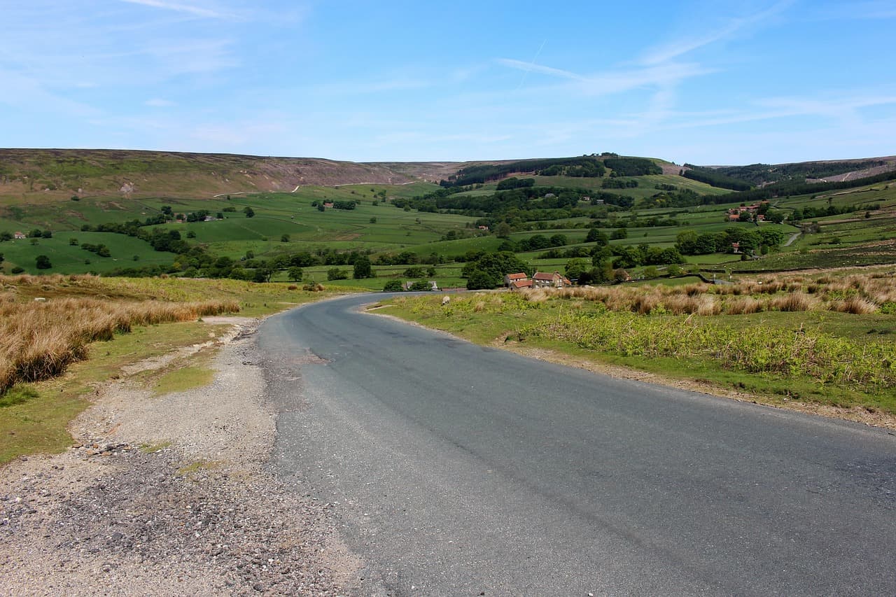 An open road running across green moorland under a big sky